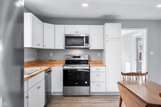 kitchen featuring sink, appliances with stainless steel finishes, white cabinetry, light hardwood / wood-style floors, and wood counters