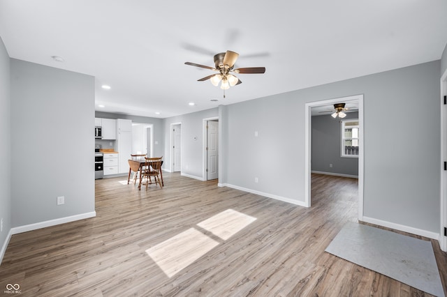 unfurnished living room featuring ceiling fan and light wood-type flooring