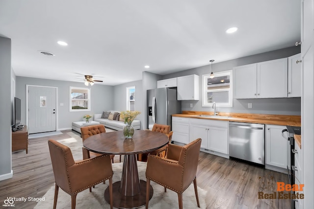 kitchen featuring butcher block counters, sink, appliances with stainless steel finishes, pendant lighting, and white cabinets