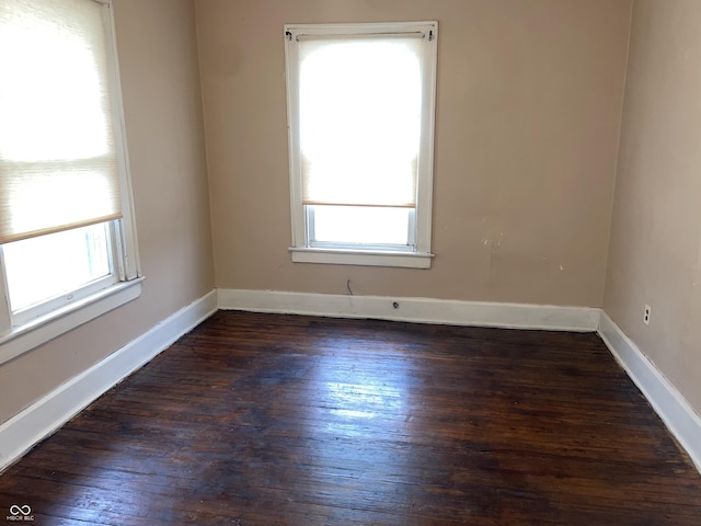 empty room with a healthy amount of sunlight and dark hardwood / wood-style flooring