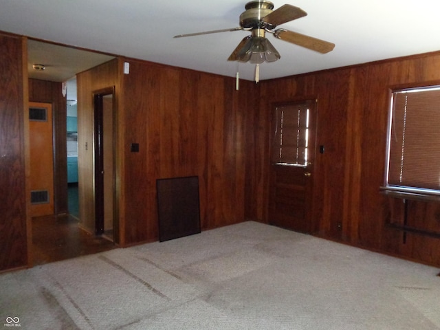 unfurnished room featuring ceiling fan, carpet flooring, and wooden walls