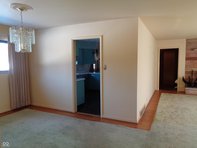 unfurnished room with an inviting chandelier and light wood-type flooring