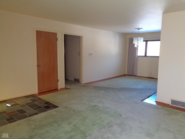 carpeted spare room with a chandelier