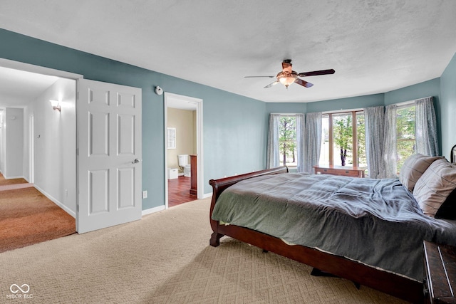 carpeted bedroom with connected bathroom, a ceiling fan, and baseboards