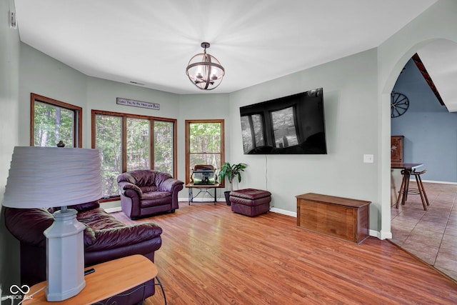 living area with baseboards, arched walkways, wood finished floors, and a notable chandelier