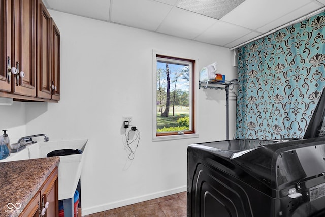 laundry room with tile patterned flooring, washing machine and dryer, cabinet space, a sink, and baseboards