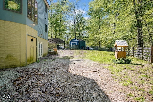 view of yard with a storage shed, fence, an outdoor structure, and a detached carport