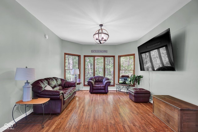 living room featuring baseboards, wood finished floors, and a notable chandelier