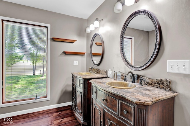 bathroom with vanity, baseboards, wood finished floors, and a healthy amount of sunlight