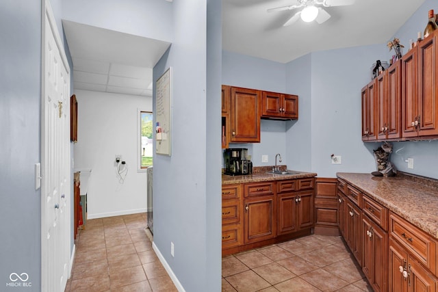 kitchen featuring brown cabinets, light tile patterned floors, ceiling fan, and a sink