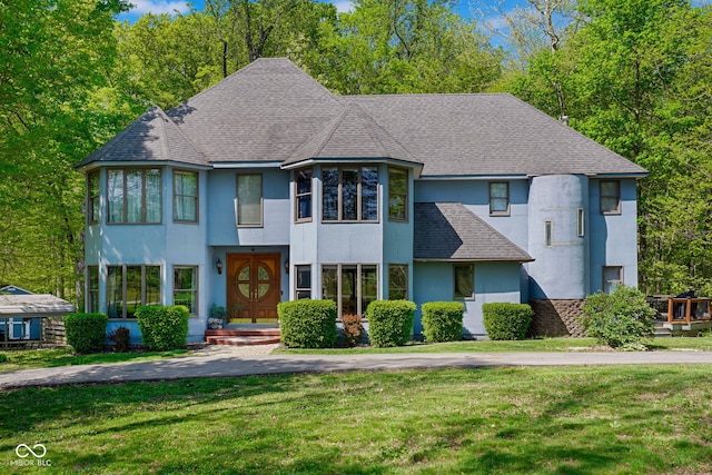 view of front of home featuring roof with shingles, stucco siding, and a front lawn