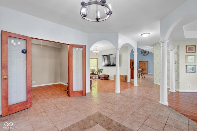 interior space featuring arched walkways, decorative columns, light tile patterned flooring, and a chandelier