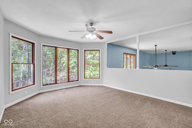 carpeted spare room featuring plenty of natural light, a ceiling fan, and baseboards