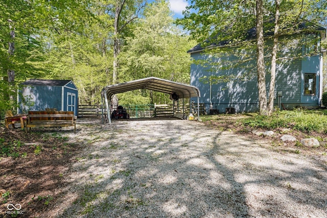 view of yard featuring an outdoor structure, a detached carport, fence, driveway, and a storage shed