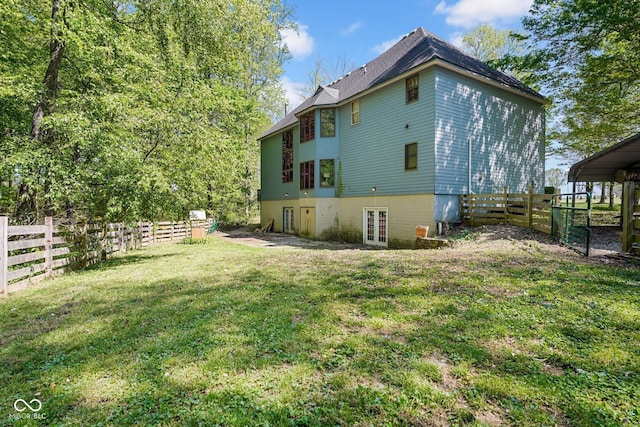 view of side of property featuring french doors, a lawn, and a fenced backyard