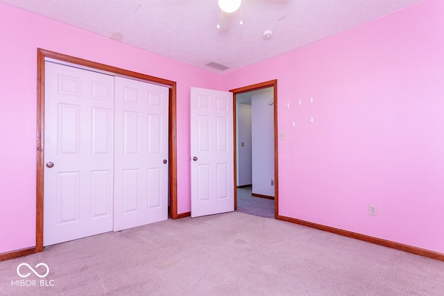 unfurnished bedroom with a textured ceiling, light carpet, ceiling fan, and a closet