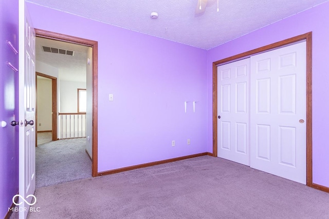 unfurnished bedroom with a textured ceiling, light carpet, and a closet