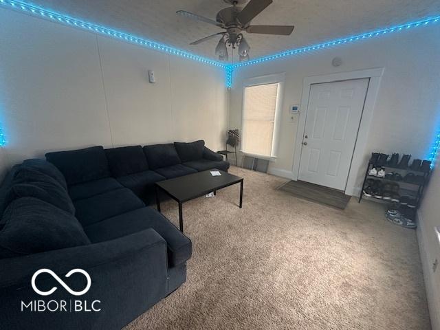 carpeted living room with ceiling fan