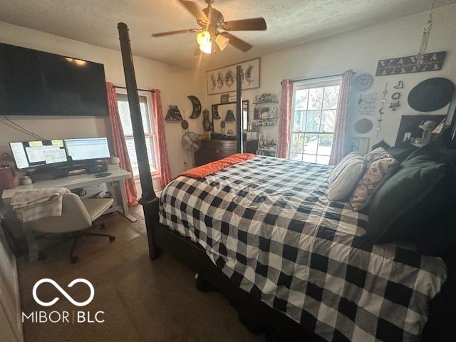 bedroom with ceiling fan, carpet floors, and a textured ceiling