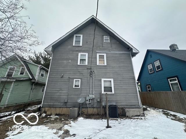 snow covered rear of property featuring central air condition unit