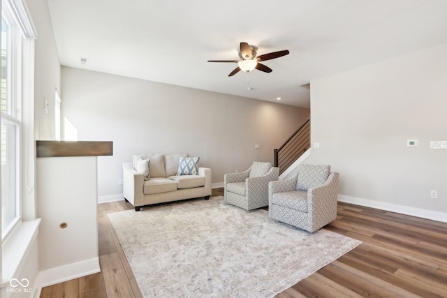 living room featuring ceiling fan, wood-type flooring, and a wealth of natural light