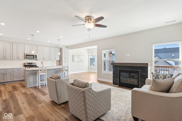 living room featuring a fireplace, ceiling fan, and light wood-type flooring