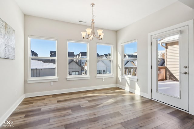 unfurnished dining area with hardwood / wood-style flooring and a chandelier