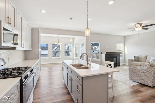 kitchen with a breakfast bar, sink, decorative light fixtures, stainless steel appliances, and decorative backsplash