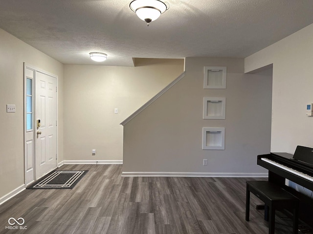 foyer entrance with dark wood-type flooring and a textured ceiling