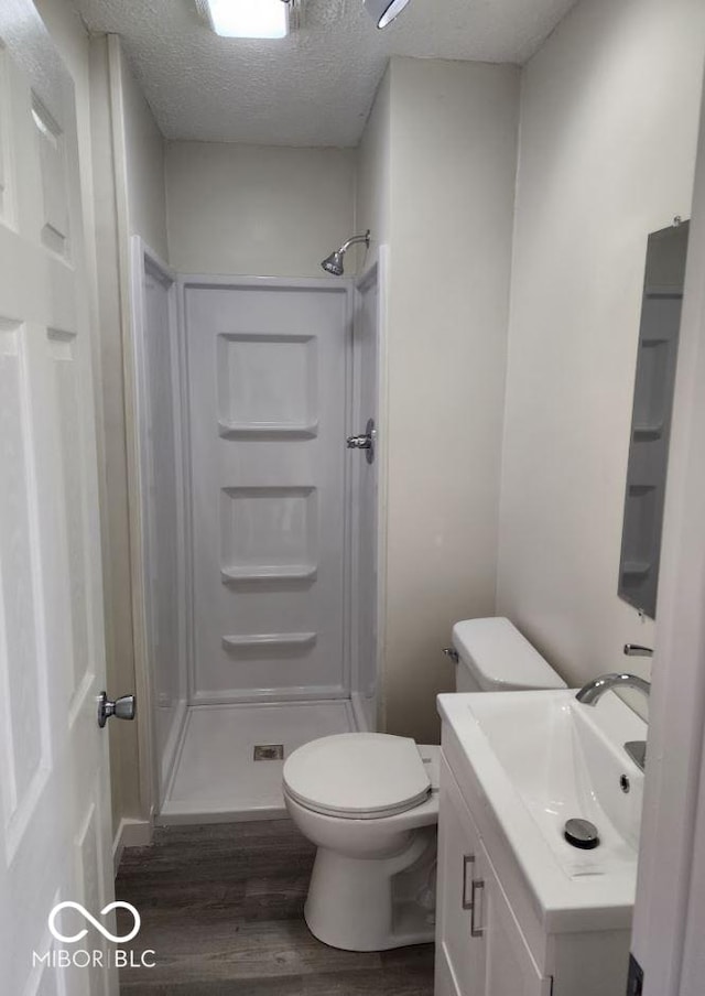 bathroom with hardwood / wood-style flooring, vanity, a shower, a textured ceiling, and toilet