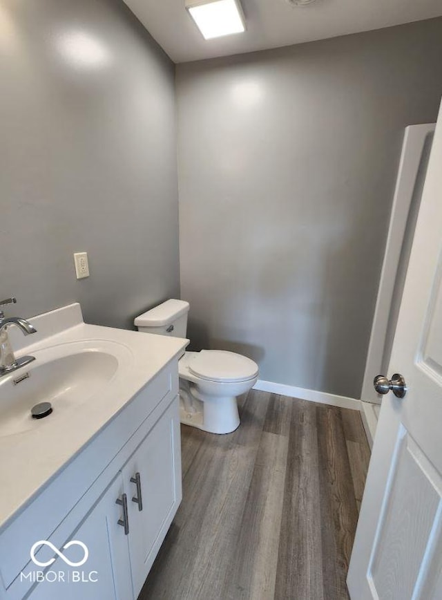 bathroom featuring wood-type flooring, vanity, and toilet