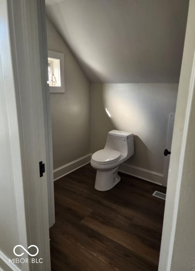 bathroom featuring wood-type flooring, vaulted ceiling, and toilet