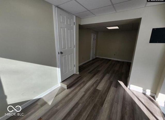 corridor with dark hardwood / wood-style floors and a drop ceiling