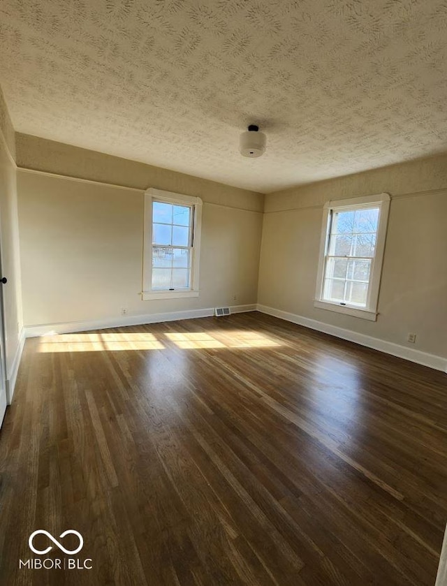 empty room with dark hardwood / wood-style floors and a textured ceiling