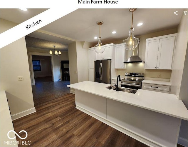 kitchen with appliances with stainless steel finishes, decorative light fixtures, white cabinets, a kitchen island with sink, and wall chimney range hood