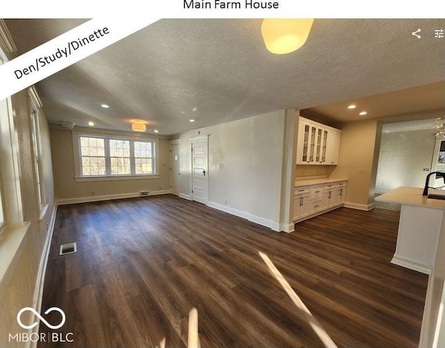 unfurnished living room featuring dark hardwood / wood-style flooring, sink, and a textured ceiling