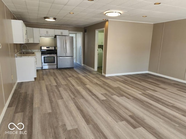 kitchen featuring washer / dryer, sink, white cabinets, light hardwood / wood-style floors, and stainless steel appliances