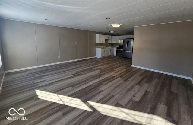 unfurnished living room featuring dark wood-type flooring and sink