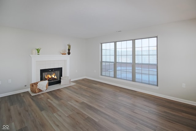 unfurnished living room with a tile fireplace and dark hardwood / wood-style floors