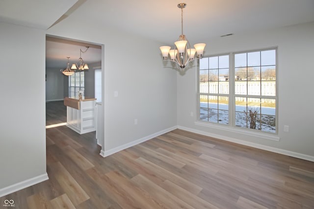 unfurnished room with hardwood / wood-style floors and a chandelier