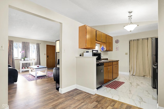 kitchen featuring pendant lighting, stainless steel appliances, a textured ceiling, and light wood-type flooring