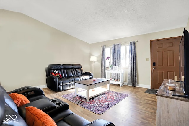 living room with lofted ceiling, light hardwood / wood-style flooring, and a textured ceiling