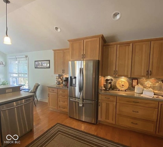 kitchen with pendant lighting, light hardwood / wood-style flooring, stainless steel appliances, tasteful backsplash, and vaulted ceiling