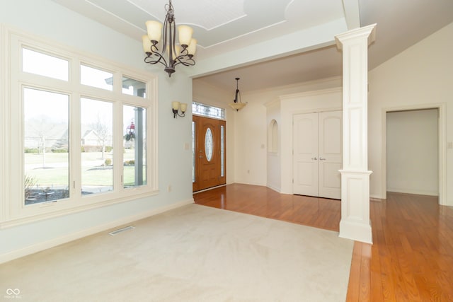 foyer entrance featuring a notable chandelier, hardwood / wood-style flooring, and decorative columns