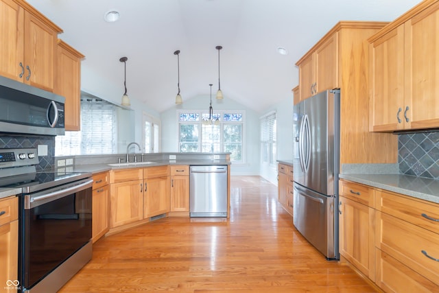 kitchen featuring sink, decorative light fixtures, vaulted ceiling, light hardwood / wood-style flooring, and stainless steel appliances