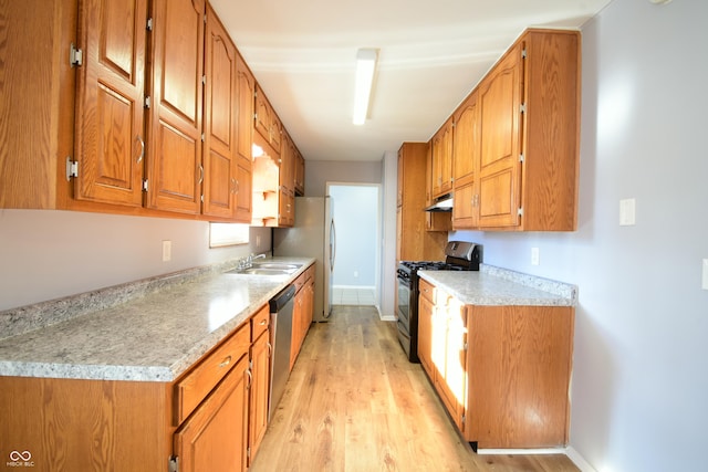 kitchen featuring light stone counters, sink, light hardwood / wood-style floors, and appliances with stainless steel finishes