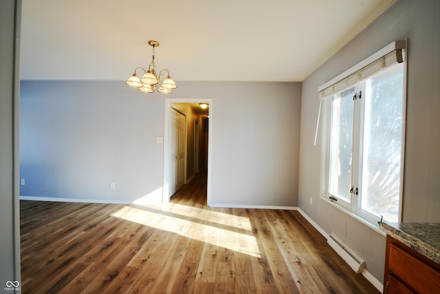 spare room featuring a baseboard radiator, a chandelier, and light wood-type flooring