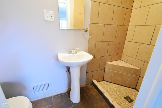 bathroom featuring sink, tile patterned floors, toilet, and tiled shower