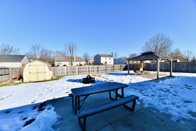 snowy yard with a gazebo and a shed