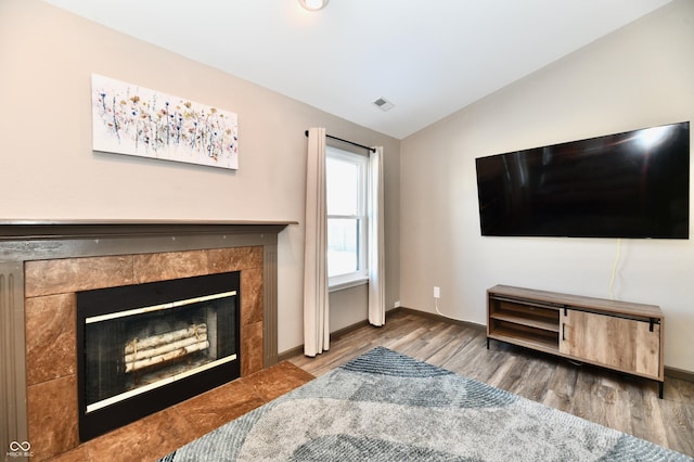 living room featuring lofted ceiling, hardwood / wood-style floors, and a fireplace